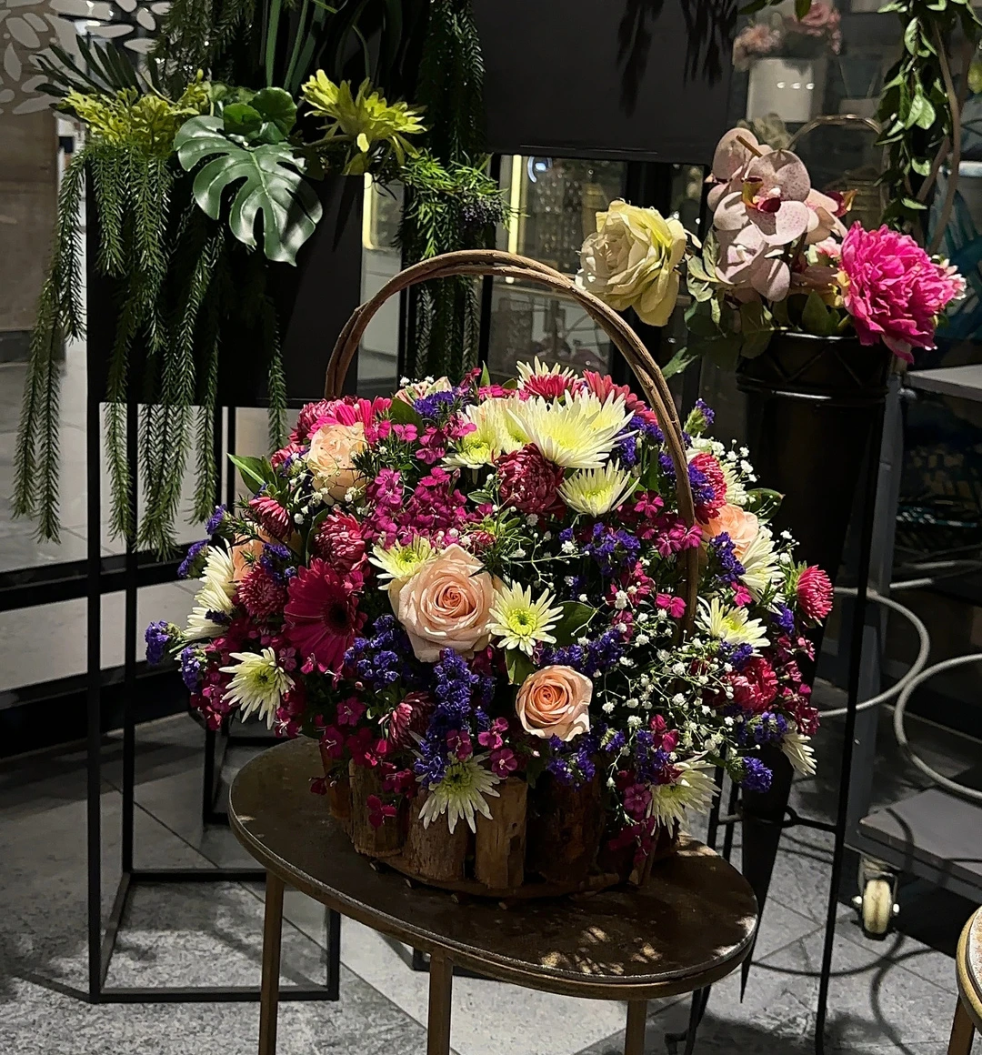 A colourful sympathy basket composed of pink, cream and purple flowers with greenery